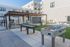 Modern outdoor recreational area featuring a sleek foosball table, shuffleboard, and stylish pergola against a backdrop of contemporary apartments.