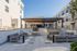 Elegant outdoor courtyard featuring modern seating, sleek pergola, and contemporary architecture under a bright blue sky.