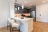 Contemporary kitchen with sleek gray cabinets, modern stainless steel appliances, and a stylish white countertop bar featuring chic pendant lighting.