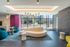 Chic apartment lobby featuring modern furniture, vibrant purple accents, and floor-to-ceiling windows with street views.