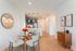 Inviting open-concept dining area with elegant glass table, plush chairs, and a modern kitchen backdrop.