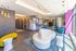 Chic and modern apartment lobby featuring a curvy white sofa, vibrant yellow and blue seating, and stylish gold lighting fixtures.