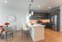 Modern kitchen with sleek gray cabinets, stainless steel appliances, and a chic breakfast bar adjoining a welcoming dining area with elegant neutral decor.