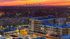 Vibrant evening cityscape featuring a modern apartment complex with skyline views and a glowing sunset backdrop.