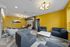 Modern lounge area with vibrant yellow walls, stylish geometric lighting, and comfortable seating arrangement for a welcoming atmosphere.