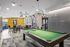 Modern recreational room featuring a chic billiards table, stylish seating area, and contemporary lighting fixtures, perfect for entertainment and relaxation.