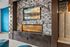 Luxurious living room corner featuring a modern marble fireplace and decorative lighting, with artful wall design and plush seating.