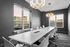 Modern conference room with sleek white tables, stylish chairs, and contemporary lighting, featuring large windows with cityscape views.