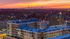 Chic urban apartment building with rooftop views overlooking a stunning city skyline at sunset.