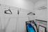 Modern walk-in closet with sleek wire shelving and stylish black hangers, complemented by contemporary artwork and decor.