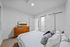 Elegant bedroom featuring a cozy bed with plush pillows, a sleek wooden dresser, and minimalist decor in a bright and inviting space.
