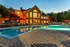 Elegant luxury apartment complex with a stunning illuminated poolside at dusk, featuring stylish outdoor seating and vibrant surroundings.