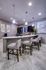 Elegant modern kitchen with a sleek countertop, stylish bar stools, and ambient pendant lighting, perfect for entertaining.
