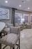 Contemporary living space showcasing chic patterned chairs, elegant lighting, and modern decor with large windows bringing in natural light.