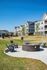 Modern apartment complex with inviting outdoor fire pit area and playground, set against a clear blue sky.