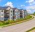 Charming modern apartment complex with beautiful architecture, spacious balconies, and lush green surroundings on a peaceful street.