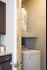 Chic apartment kitchen with elegant dark cabinetry, sleek granite countertops, and modern appliances, featuring a convenient adjacent laundry room with stacked washer and dryer.
