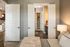 Inviting bedroom with elegant double doors leading to a chic walk-in closet and a modern en-suite bathroom, accented by warm lighting and stylish decor.