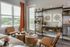 Chic living room with stylish shelving, modern art, and cozy seating bathed in natural light from large windows.