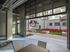 Modern apartment courtyard with red lounge chairs, large screen outdoor entertainment, and spacious seating area.