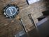 Chic bar with sleek taps and a rustic wood-paneled backdrop, featuring a stylish illuminated 'P The Cave' sign.