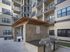 Chic apartment courtyard featuring dual stainless steel grills under a stylish pergola, surrounded by modern facades and inviting balconies.