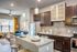Modern apartment interior showcasing an elegant open-concept kitchen with granite countertops, adjacent to a cozy living area with a plush blue sofa and vibrant yellow curtains.