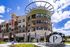 Modern apartment building exterior at Promontory with elegant architectural design, featuring large windows and vibrant landscaping, under a bright blue sky.