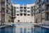 Luxurious apartment complex featuring a pristine swimming pool surrounded by stylish lounge chairs, perfect for relaxation and leisure.