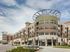 Modern apartment complex with sleek architectural design and spacious balconies, featuring a prominent entrance and lush landscaping.