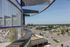 Breathtaking urban view from a modern balcony showcasing cityscape and open parking space beneath clear skies.