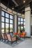 Luxurious living area with high ceilings, expansive windows, and elegant orange and wicker furniture offering a scenic outdoor view.