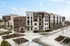Modern apartment complex showcasing a blend of brick and stone exteriors, featuring multiple stories with balconies, ample parking, and lush landscaping.