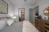 Chic bedroom highlighted by modern decor, plush bedding, and elegant lighting connecting to a stylish hallway with wooden accents.