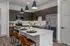 Modern kitchen with sleek dark cabinets, stainless steel appliances, and a stylish island with bar seating and pendant lighting.