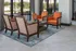 Chic sitting area featuring vibrant orange chairs and patterned lounge seats, set against large windows with plenty of natural light.