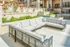 Luxurious outdoor patio with elegant sectional seating, lush greenery, and a cozy fire pit, perfect for relaxation and entertaining.