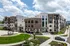 Elegant modern apartment building with stylish brick facade, featuring lush landscaping and a welcoming entrance under a vibrant blue sky.