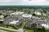 Aerial view of a modern apartment complex with ample parking, surrounded by greenery and recreational facilities in a vibrant neighborhood.