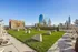 Chic rooftop terrace with plush seating, lush green lawn, and a large outdoor screen offering stunning city skyline views.