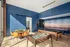 Modern recreation room with vibrant blue walls, featuring a chic wooden table with orange chairs, a pool table, and a foosball table, perfect for entertaining.
