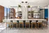 Modern kitchen space with a large island and stylish wooden chairs, featuring elegant lighting and lush plants for a vibrant atmosphere.