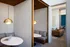 Modern apartment interior featuring cozy alcove seating with round tables under stylish pendant lights, adjacent to a chic lounge area with contemporary furniture and artwork.