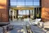 Stunning modern indoor-outdoor living space featuring sleek glass doors, cozy seating, and an elegant fire pit with city views.
