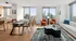Modern open-concept living and dining area with breathtaking skyline views, featuring a luxurious white sofa, chic orange armchairs, and elegant dining setup.