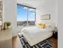 Bright bedroom with floor-to-ceiling window offering stunning city views, featuring a cozy bed with vibrant pillows, modern decor, and hardwood floors.