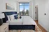 Luxurious bedroom with a plush velvet bed and skyline view, featuring elegant decor and large window for natural light.