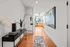 Elegant apartment hallway with modern decor, wooden flooring, and a glimpse of city skyline through a distant window.
