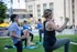 Vibrant outdoor fitness class with diverse group exercising together on green lawn in the city.