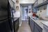 Charming kitchen with modern black appliances, sparkling granite countertops, and elegant cabinetry, leading to a cozy bathroom.